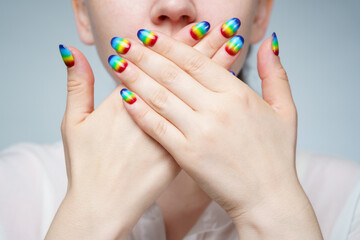 Photo of woman with rainbow manicure covering her mouth