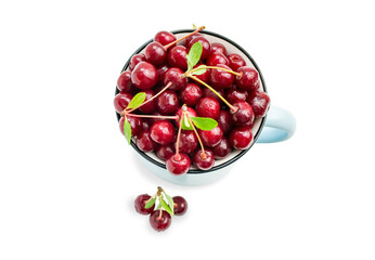 Top view of red ripe cherry in a blue mug and three berries in front. Sweet tasty fruits with water droplets in a cup isolated on white background. Healthy food, summer harvest. Summertime vitamins.