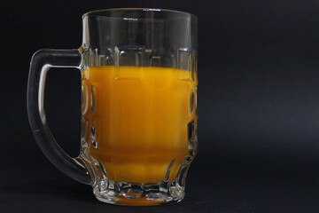 Full glass of orange juice on a black background