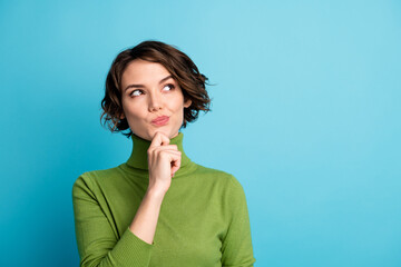 Portrait of minded interested girl touch finger chin look copyspace think thoughts decide decision wear green jumper isolated over blue color background