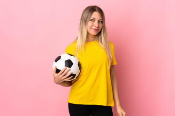 Young football player woman isolated on pink background standing and looking to the side