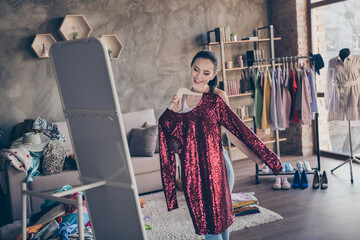 Portrait of her she nice attractive cheerful cheery girl holding in hand new chic glamorous dress looking at mirror flattering trying in modern loft industrial interior apartment