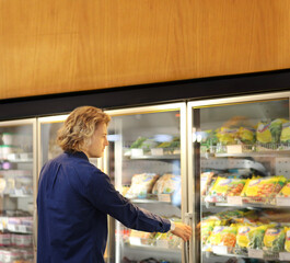 Fototapeta na wymiar Man choosing frozen food from a supermarket freezer 