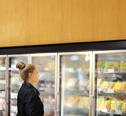 Woman choosing frozen food from a supermarket freezer	