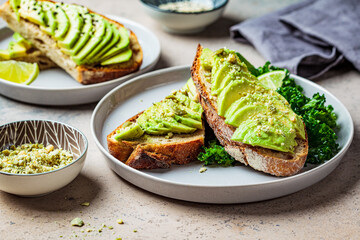 Avocado toasts with seeds on a gray plate. Plant based diet concept.