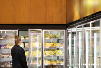 Woman choosing frozen food from a supermarket freezer	