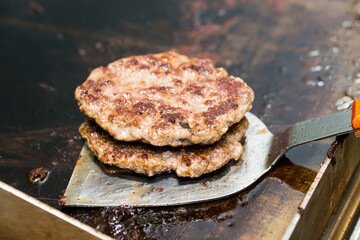fried meat patties with hamburger on a metal spatula