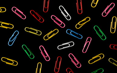 Colorful paperclips isolated on black background, top view