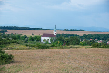 Fototapeta na wymiar Catholic church in a village with trees and field.