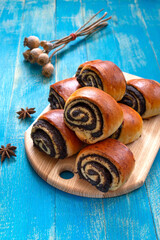 Tasty buns rolls with poppy filling on a blue wooden background. Vertical view