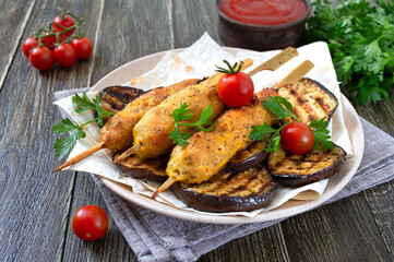 Lula kebab with grilled eggplant on pita bread. Dietary chicken kebabs on a skewer with vegetables.