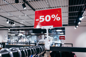 Red SALE label on clothes rack in the woman clothing shop.