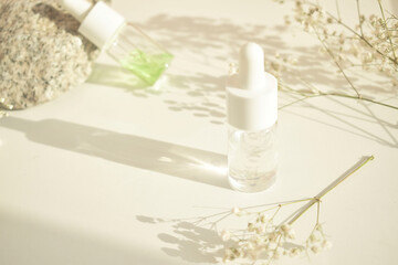 Bottles of essential cosmetic oil in a glass bottle on a white table with a natural background. Aromatherapy oil, the concept of natural cosmetics. Space for text.