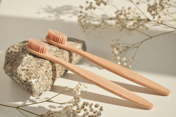 Natural bamboo toothbrush on a white background with a decor of natural stone and flowers. Plastic...