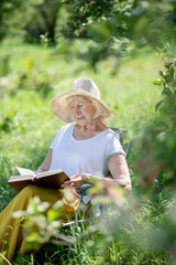 Elegant elderly woman reading a book in the fresh air