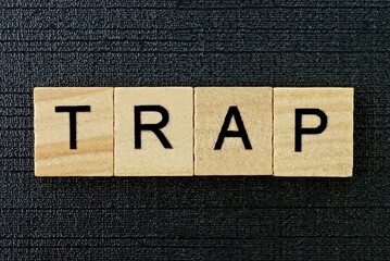 gray word trap from small wooden letters on a black table