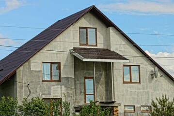 facade of a gray private house with brown windows against a blue sky