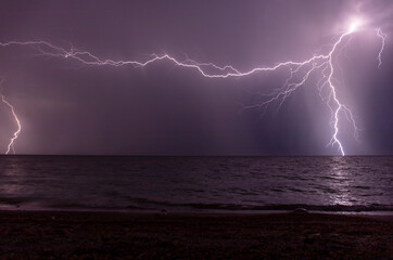 Naklejka na ściany i meble night shooting of a thunderstorm over the sea, photography of lightning