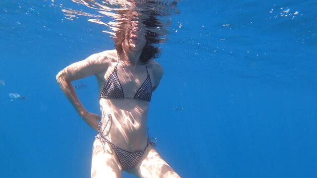 woman putting on her bikini in mediterranean sea under the water