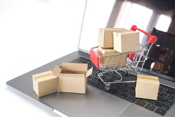 Paper cartons or parcel in the cart on laptop keyboard. Shopping service on online web and offers home delivery. online shopping concept.