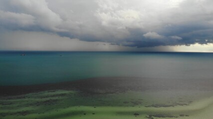 Stormy sky and unusual coast of white sand. Breathtaking landscape of stormy cloudy sky and sandy wavy white seaside in bright day. Thunderstorm in the tropics. Paradise islands in Asia. Drone view