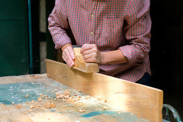 Craftswoman working with old wooden jointer plane, wood shaving concept.