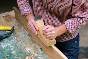 Female carpenter working with old wooden jointer plane, wood shaving concept.