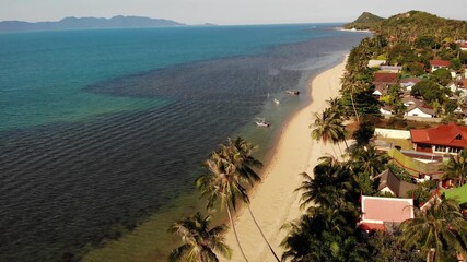 Road and houses on seashore. Drone view of main road and coastal cottages on Ko Samui Island on sunny day in Thailand. Bang Po exotic tropical beach.