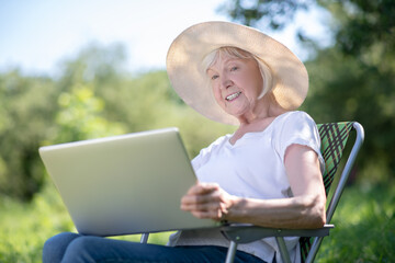 Fototapeta premium Elderly woman working with the computer outdoor