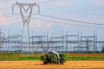 Electric power masts around barn. Power plant in background.