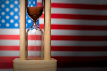 Hourglass and USA flag, soft focus, copy space