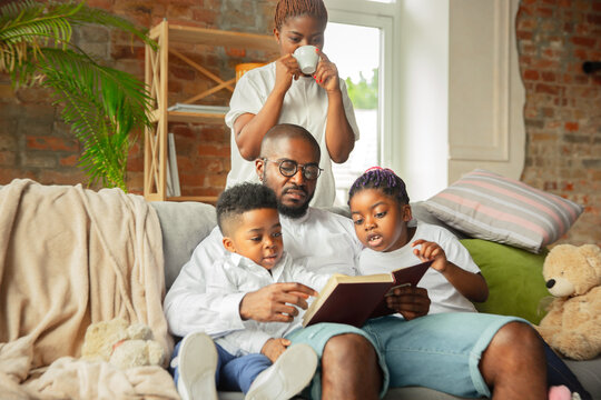 Reading. Young And Cheerful African Family During Quarantine, Insulation Spending Time Together At Home. Time For Family, Happiness And Love. Concept Of Quarantine Lifestyle, Togetherness, Home