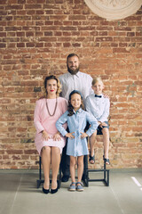 Obraz na płótnie Canvas Classic. Happy family traditional portrait, old-fashioned. Cheerful parents and kids in official styled attire on dark vintage background. Concept of human emotions, memories, togetherness, fun.