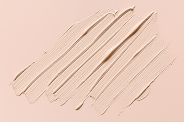 Liquid foundation makeup cream brushstrokes on beige background. Nude color cosmetic product texture
