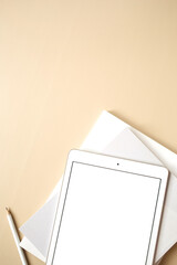 Tablet pad with blank touch screen on neutral beige background. Flat lay, top view empty mockup...