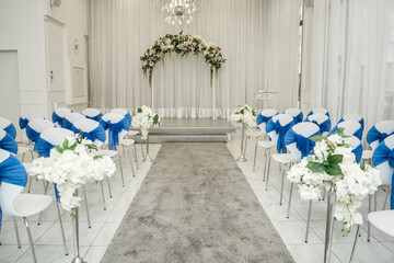 Bright room for weddings. Rows of guest chairs decorated with blue cloth