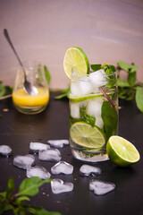 Summer coctail mojito with ice, mint, lime on a grey background. Copy space.