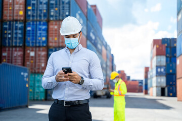 Business man wearing protective mask to Protect Against Covid-19 worker checking container box with...