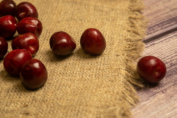 Ripe juicy cherries scattered on a homespun fabric with a rough texture. Close up.