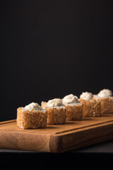 Sushi rolls with sesame seeds on a wooden dummy board. Vertical orientation. Japanese traditional cuisine concept.