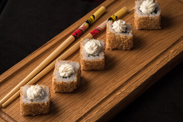 Savory rolls with sesame seeds on a wooden board. Japanese food concept.