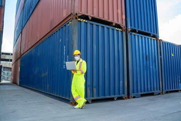 Engineer worker in protective safety jumpsuit uniform use laptop computer checking product at cargo container shipping warehouse.