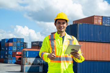 Young worker man with digital tablet at container terminal port,Business Logistics import export...