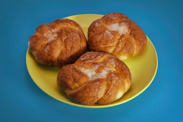 Freshly baked bun with a crispy crust close-up on a blue background.