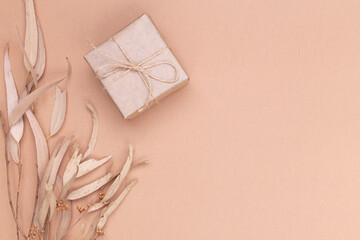 Autumn composition. Gifts wrapped in kraft paper, autumn eucalyptus leaves, on a beige background. Flat lay, top view, copy space