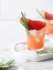 Grapefruit lemonade. Two cold wet drinking glasses with fresh grapefruit nonalcohol beverage. Ice, rosemary.