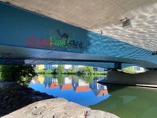 Brücke von unten Graffiti auf Beton,  Fluß Häuserreihe spiegelt sich im Wasser