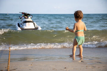 cute toddler kid playing with sea waves back view