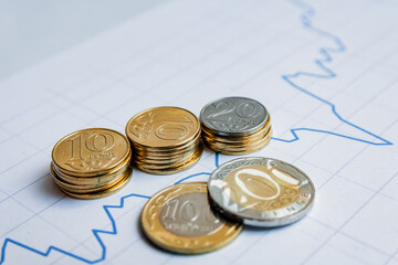 coins stacked in a row and in columns on the graph of the growth of finance