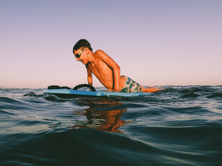 A young boy playing with a body table  in the water in the sunset time in summer